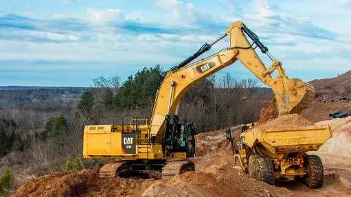 Hydraulic excavator loading a haul truck at a utility dig