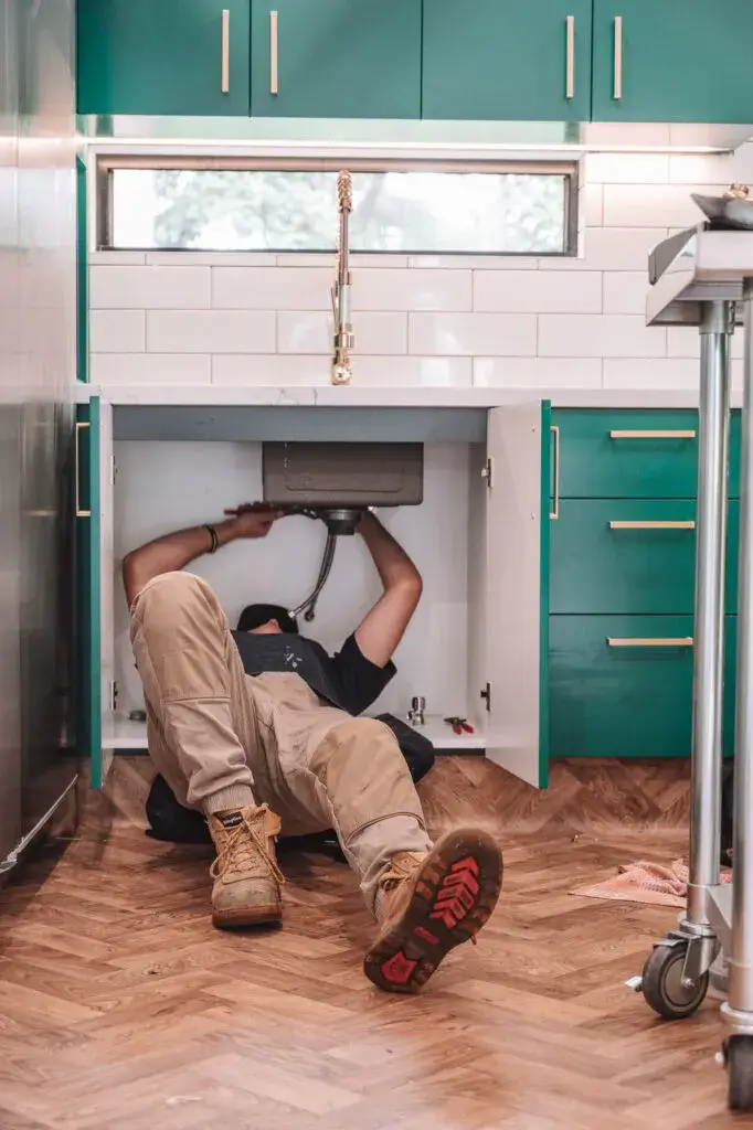 Plumber working under a kitchen sink during an inspection