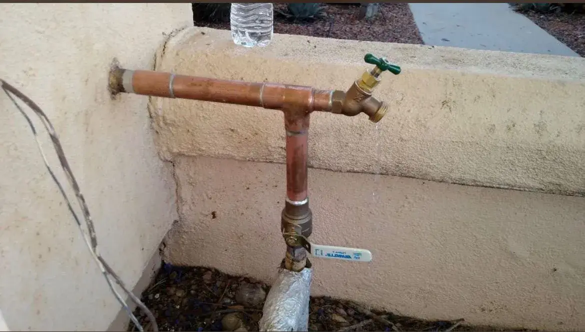 Copper hose bib installed on a stucco wall