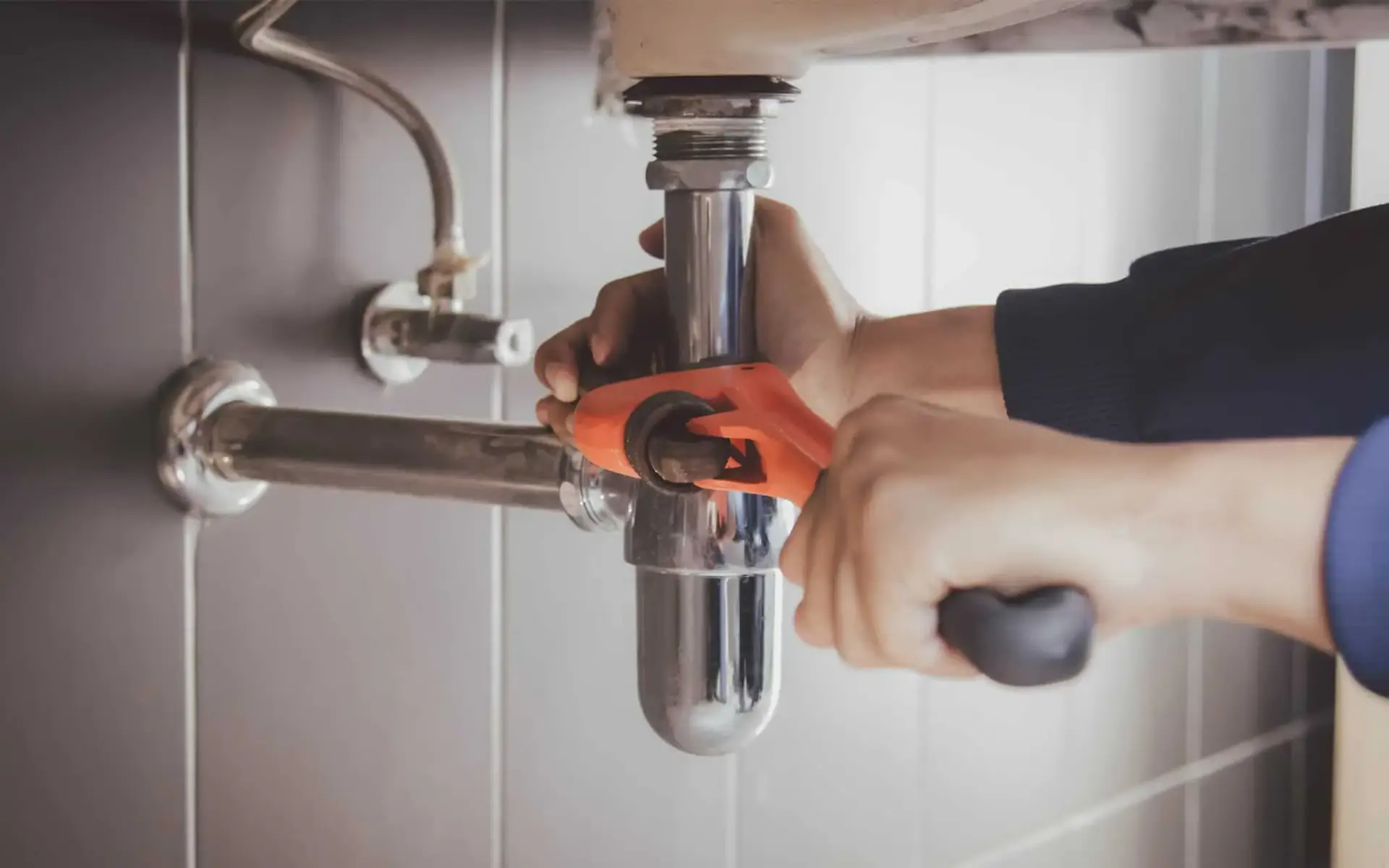 Plumber tightening a sink trap during a repair
